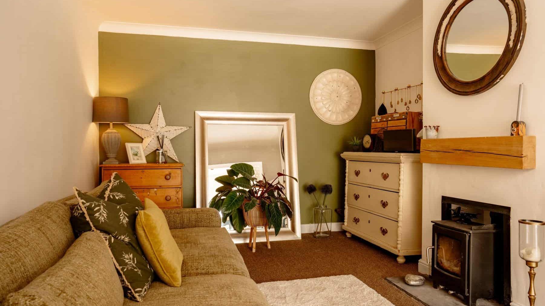 A cozy living room with a large beige sofa, vintage wooden furniture, and a fireplace, decorated with various plants and wall-mounted ornaments. warm lighting enhances the tranquil ambiance.