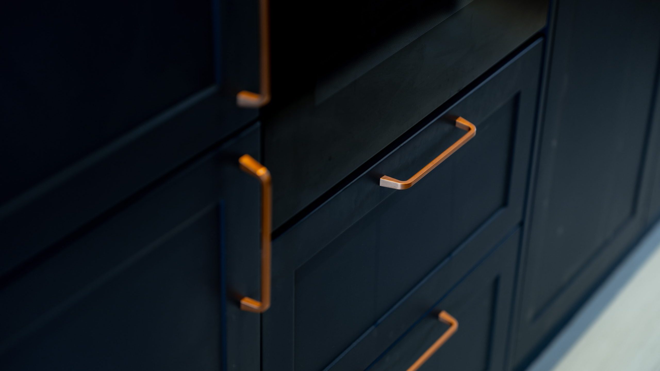 Close-up of dark blue cabinet drawers with modern, matte gold handles, highlighting the sleek and contemporary design of the cabinetry.